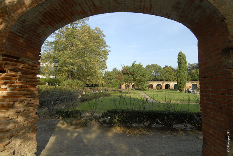 Cloître Arsenal, arcade en briques et jardin